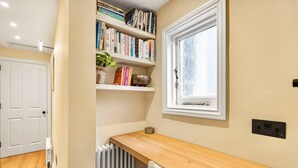 A room with a wooden desk, bookshelves, a radiator, and a window. - Notting Hill 4-bed Private Garden Home Office (London)