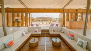 A spacious lounge area with a long white sofa, two round wicker tables, and purple woven chairs. - The Anmon Resort Bintan (Bintan)