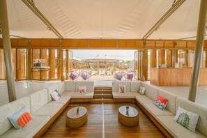 A spacious lounge area with a long white sofa, two round wicker tables, and purple woven chairs. - The Anmon Resort Bintan (Bintan)