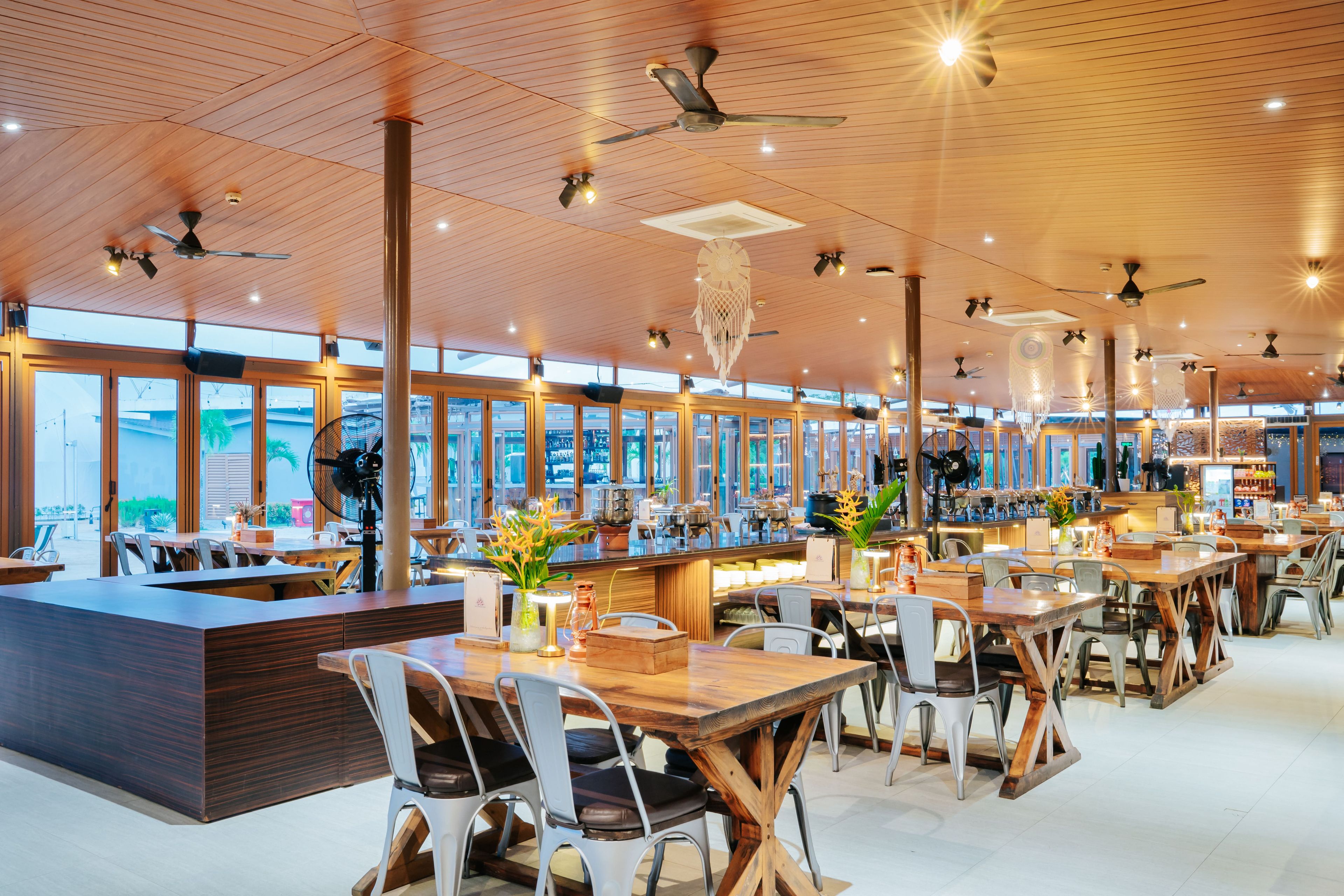 A spacious restaurant with high ceilings, wooden beams, and large windows offering views of the city.