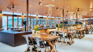 A spacious restaurant with high ceilings, wooden beams, and large windows offering views of the city. - The Anmon Resort Bintan (Bintan)