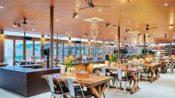 A spacious restaurant with high ceilings, wooden beams, and large windows offering views of the city.