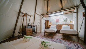 A tent-style room with two beds, a wooden bench, a small table, and a mirror. - The Anmon Resort Bintan (Bintan)