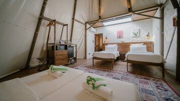 Een tent-achtige kamer met twee bedden, een houten bank, een kleine tafel en een spiegel.
