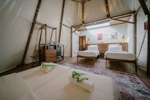A tent-style room with two beds, a wooden bench, a small table, and a mirror. - The Anmon Resort Bintan (Bintan)