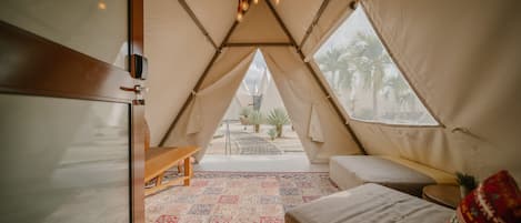 Una carpa acogedora con piso estampado, un banco de madera, un espacio de descanso con cojines y una lámpara colgante.