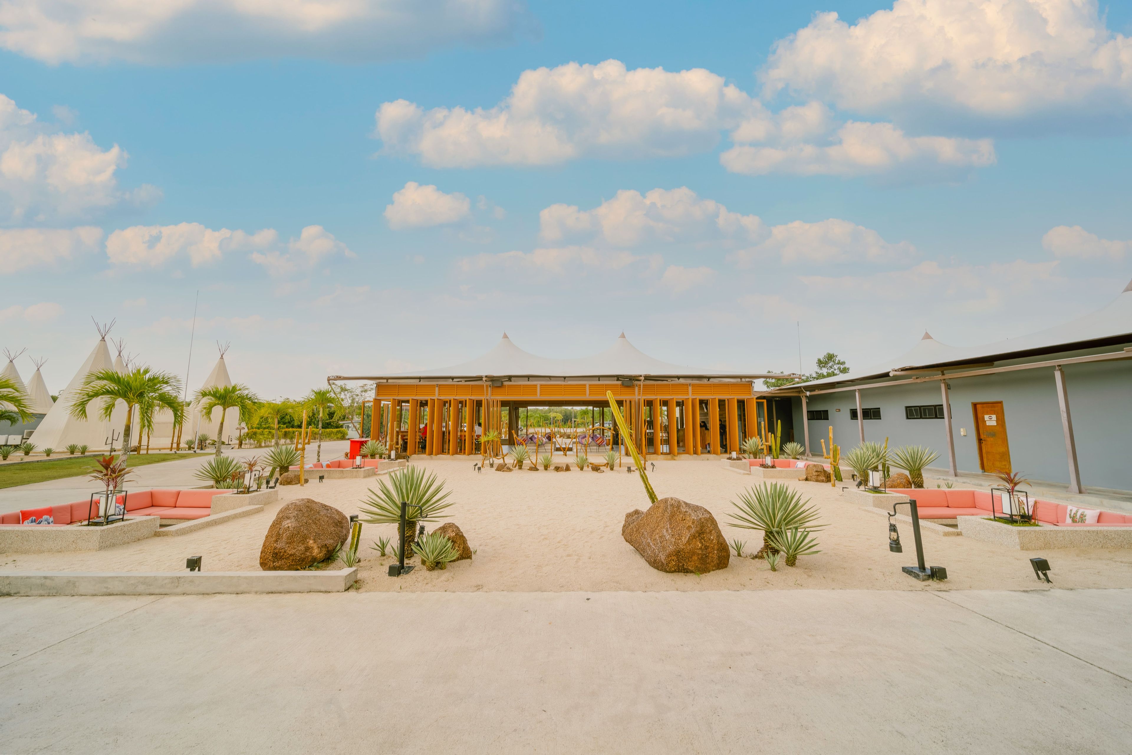 A spacious courtyard with a central wooden pavilion, surrounded by seating areas and cacti.