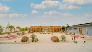 A spacious courtyard with a central wooden pavilion, surrounded by seating areas and cacti.