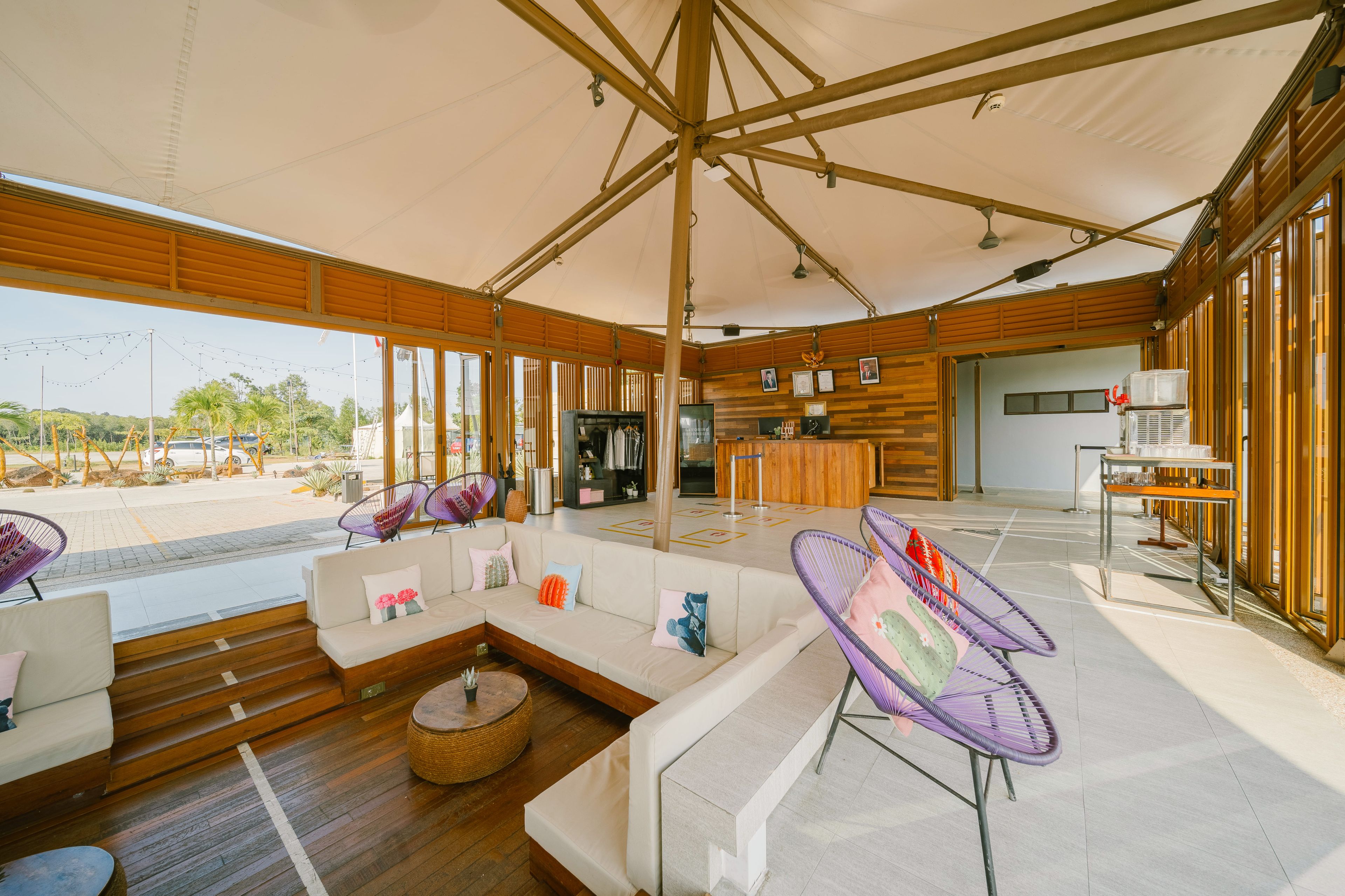 Un espacio interior amplio con una zona diáfana, suelo de madera y un área de descanso con sofás y sillones.