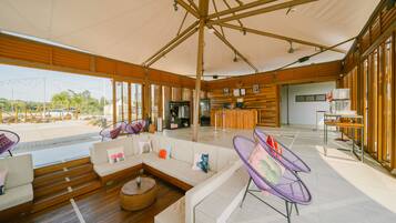 Un espacio interior amplio con una zona diáfana, suelo de madera y un área de descanso con sofás y sillones.