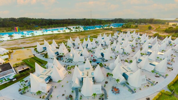 An aerial view of a resort with numerous white pyramid-shaped structures, a pool area, and a beach in the background. - The Anmon Resort Bintan (Bintan)