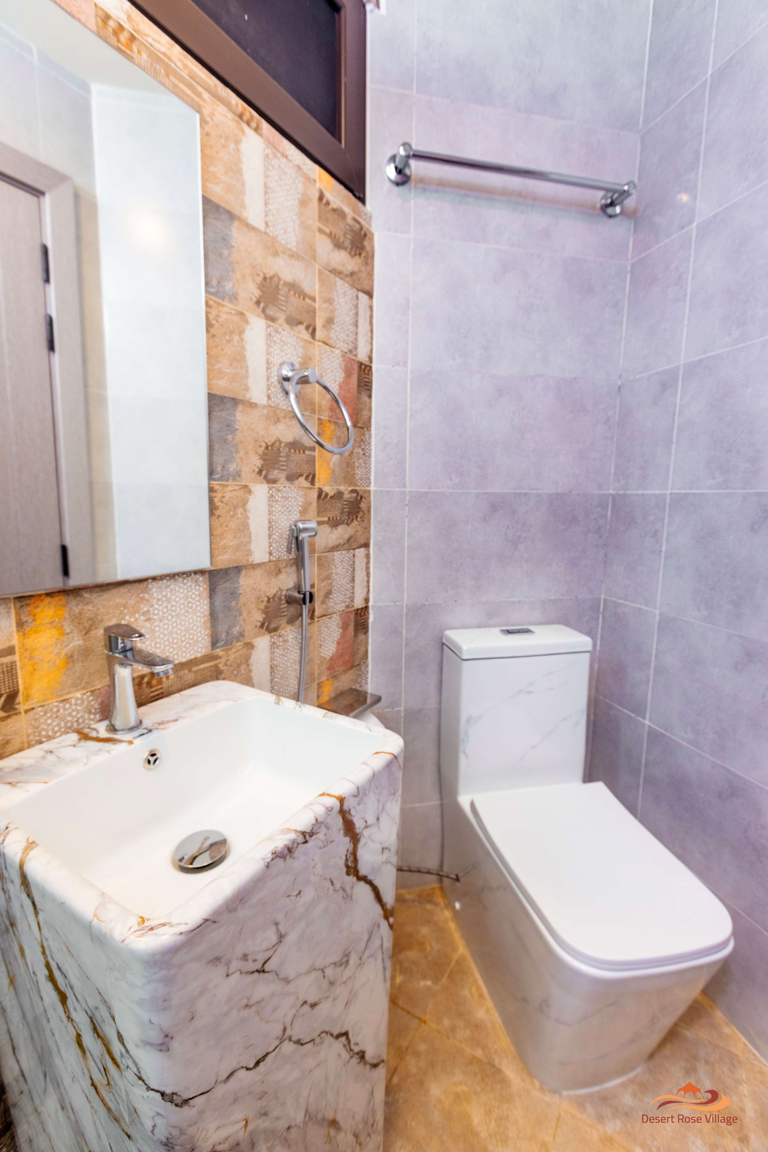A bathroom with a marble sink, a toilet, and a shower area.