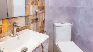 A bathroom with a marble sink, a toilet, and a shower area.