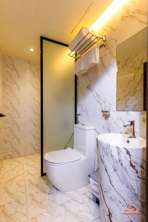 A modern bathroom with a toilet, sink, and mirror. - Desert Rose Village (Abu Dhabi)