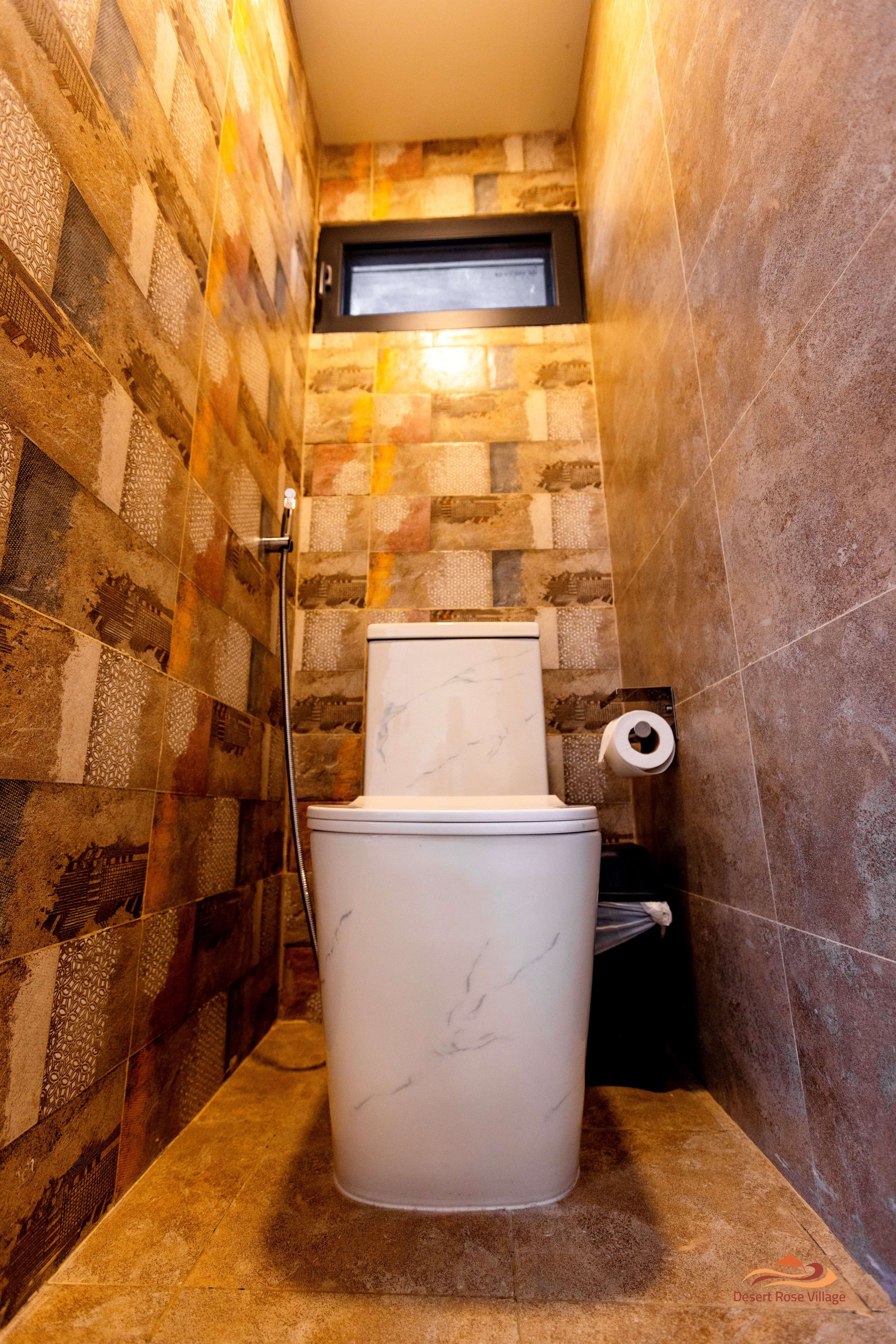 A bathroom with a toilet, a shower, and a wall-mounted toilet paper holder.