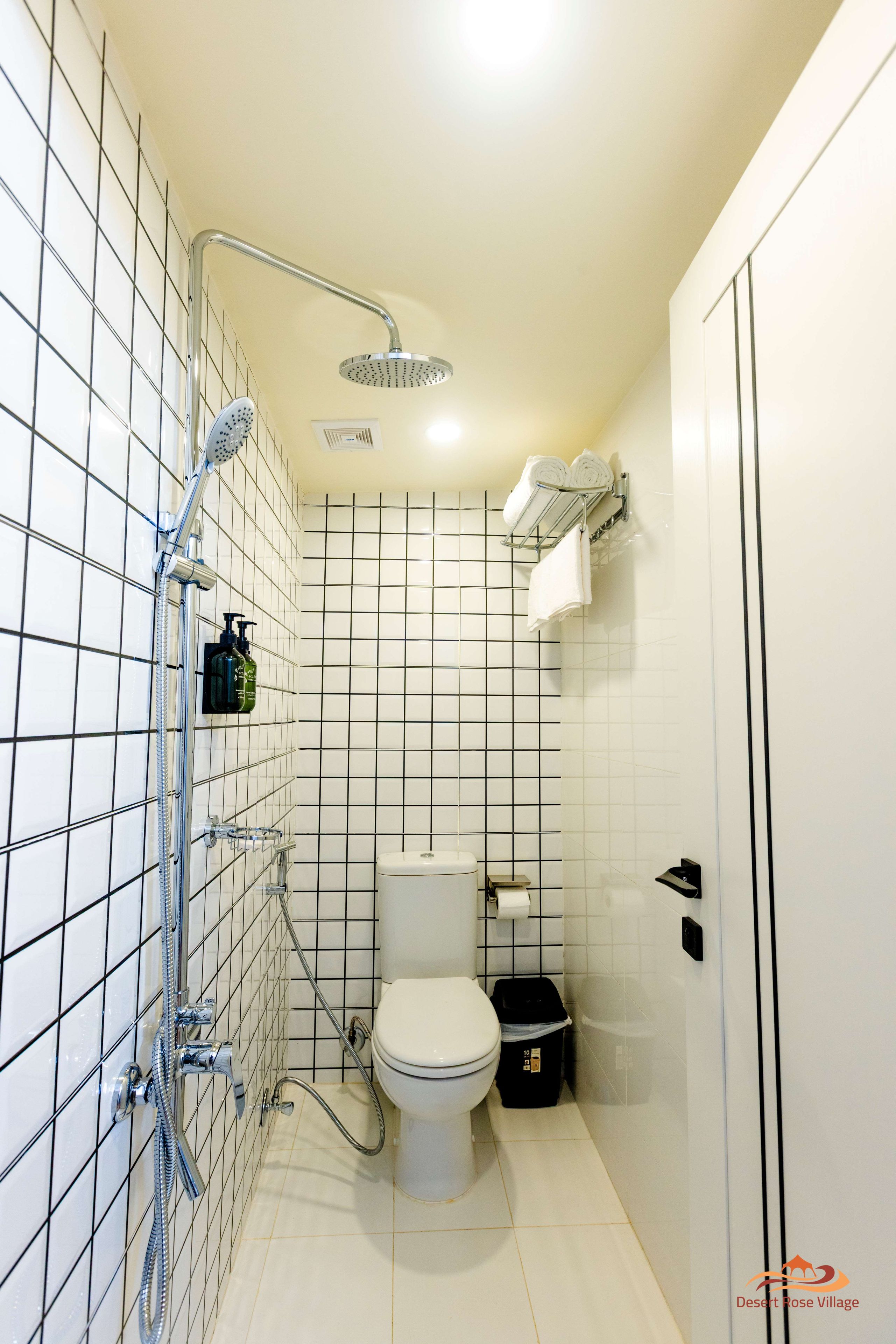 A compact bathroom with a shower, toilet, and storage shelves.