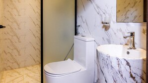A modern bathroom with a toilet, sink, and mirror. - Desert Rose Village (Abu Dhabi)