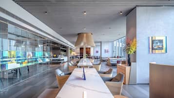 A modern hotel lobby with a marble reception desk, comfortable seating, and glass partitions.