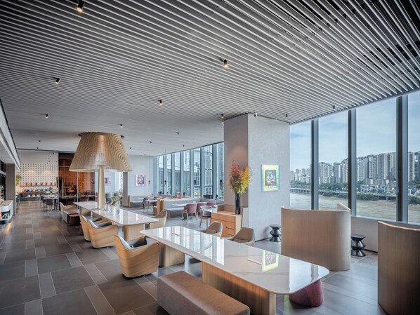 A modern hotel lobby with a large open space, seating areas, and a view of a cityscape through large windows. - Pagoda Hotel Chongqing Near By Liziba Hongya Cave (Chongqing)