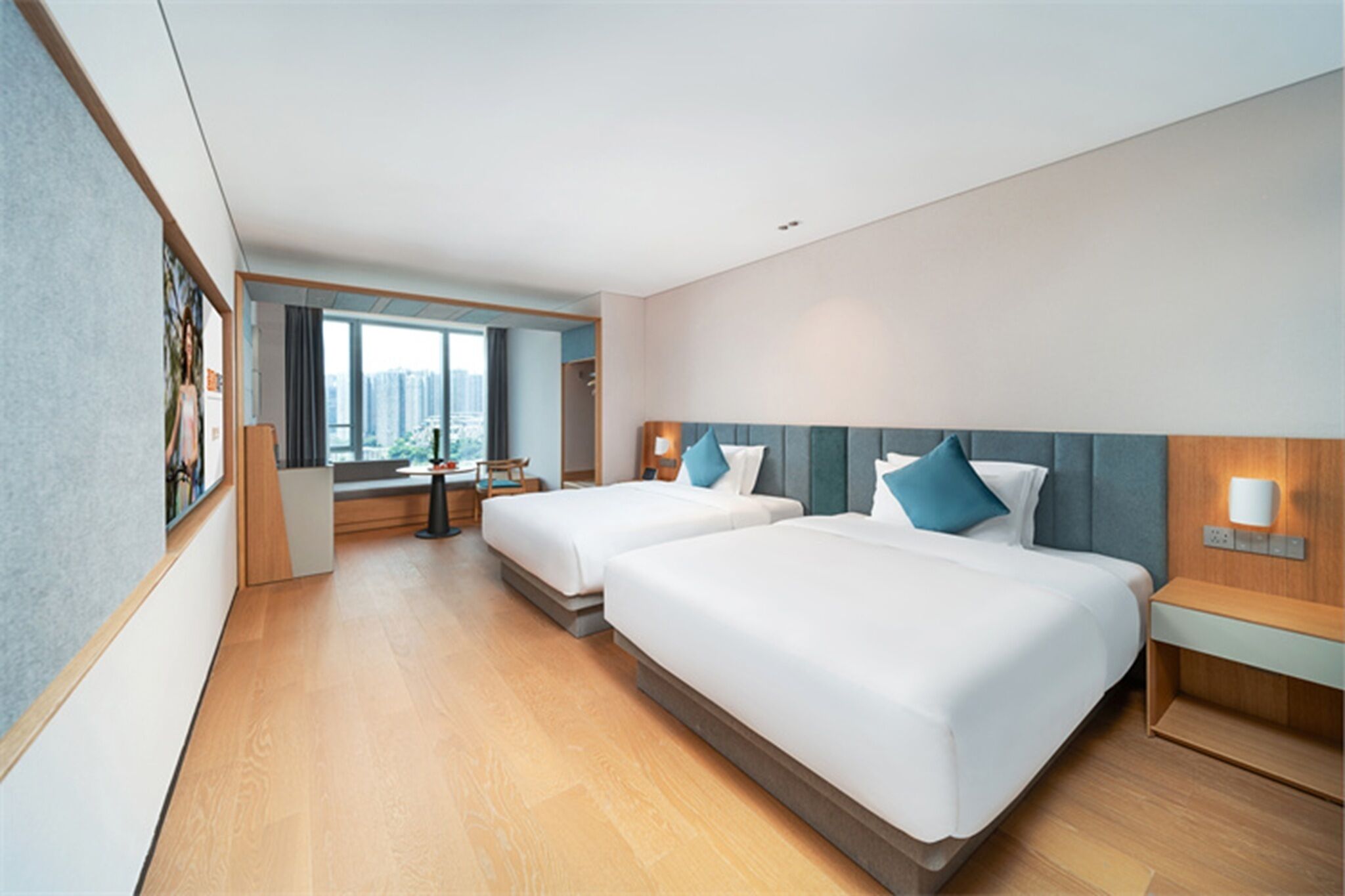 Habitación de hotel con dos camas, un escritorio y vistas a la ciudad.