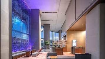 A modern lobby with a glass wall, seating area, and a reception desk.