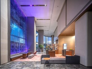 Un hall d’entrée moderne avec un mur en verre, un espace salon et un comptoir d’accueil.