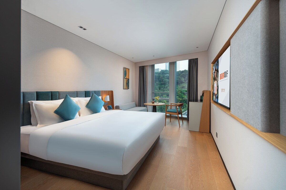 Une chambre d’hôtel avec un grand lit, un bureau et une vue sur l’extérieur.