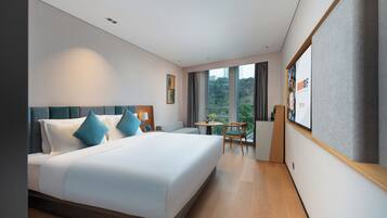 A hotel room with a large bed, a desk, and a view of the outdoors.