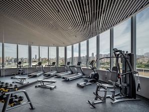 A modern gym with treadmills, weight machines, and benches, featuring large windows and a city view. - Pagoda Hotel Chongqing Near By Liziba Hongya Cave (Chongqing)