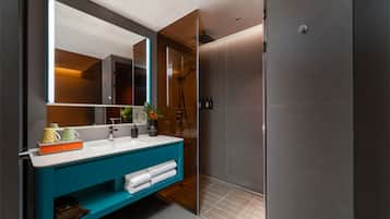 A modern bathroom with a large mirror, a blue vanity, and a walk-in shower.