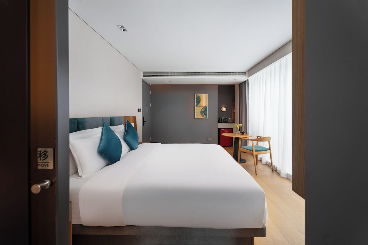 Une chambre d’hôtel avec un grand lit, un petit bureau et une chaise.