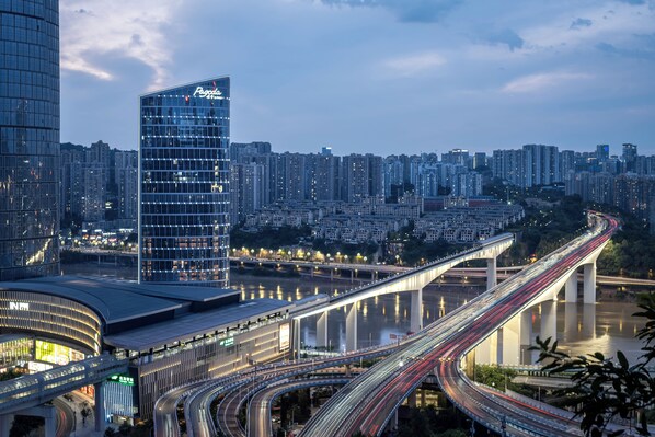 A modern urban landscape with a prominent high-rise building, a complex highway interchange, and a river. - Pagoda Hotel Chongqing Near By Liziba Hongya Cave (Chongqing)