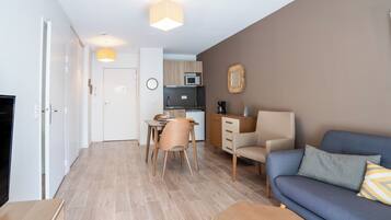 Un salon moderne comprenant un canapé, une table à manger avec des chaises, un coin cuisine et une porte.