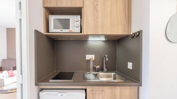 Una kitchenette compacta equipada con microondas, lavaplatos y fregadero.