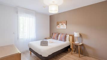 Una camera da letto con un letto, un comodino, una lampada e un quadro appeso al muro.