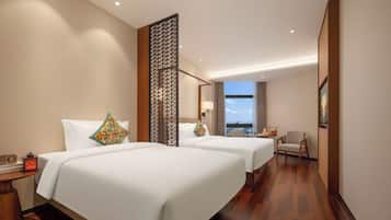 A hotel room with two beds, a nightstand, a chair, and a view of the cityscape.