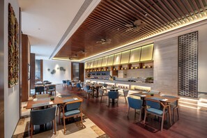 A modern restaurant with wooden flooring, blue upholstered chairs, and a long counter with a kitchen visible in the background. - Ssaw Boutique Hotel Swufe Chengdu (Chengdu)