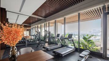 Un gimnasio moderno con cintas de correr, equipo de ejercicio y amplias ventanas con vistas a la ciudad.