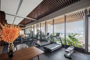 A modern gym with treadmills, exercise equipment, and large windows offering a city view. - Ssaw Boutique Hotel Swufe Chengdu (Chengdu)