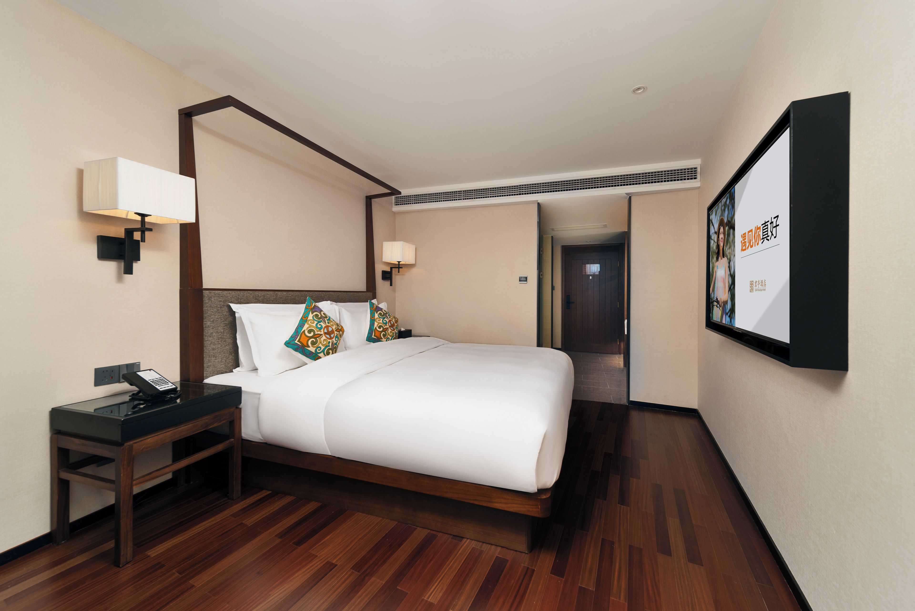 A hotel room with a bed, bedside tables, lamps, and a wall-mounted TV.