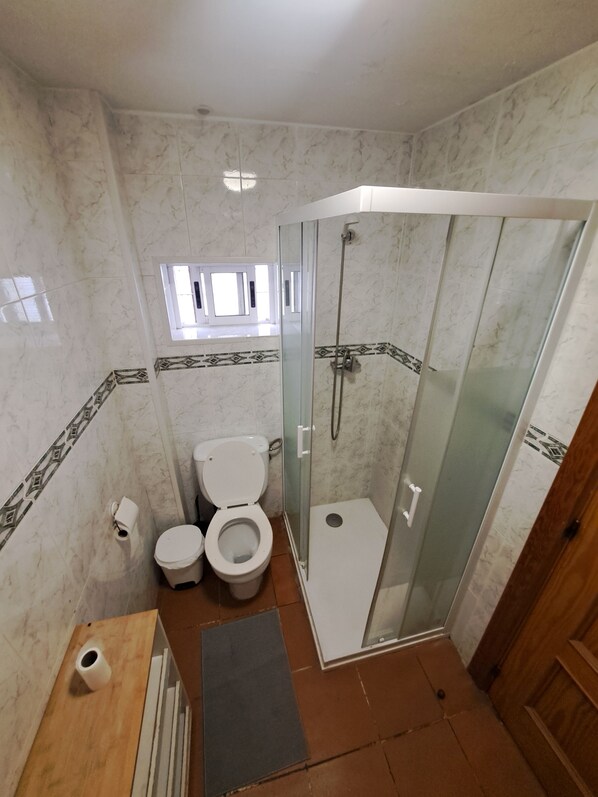 A bathroom with a toilet, a bidet, and a glass-enclosed shower stall. - Hostal Cascabel (Granada)