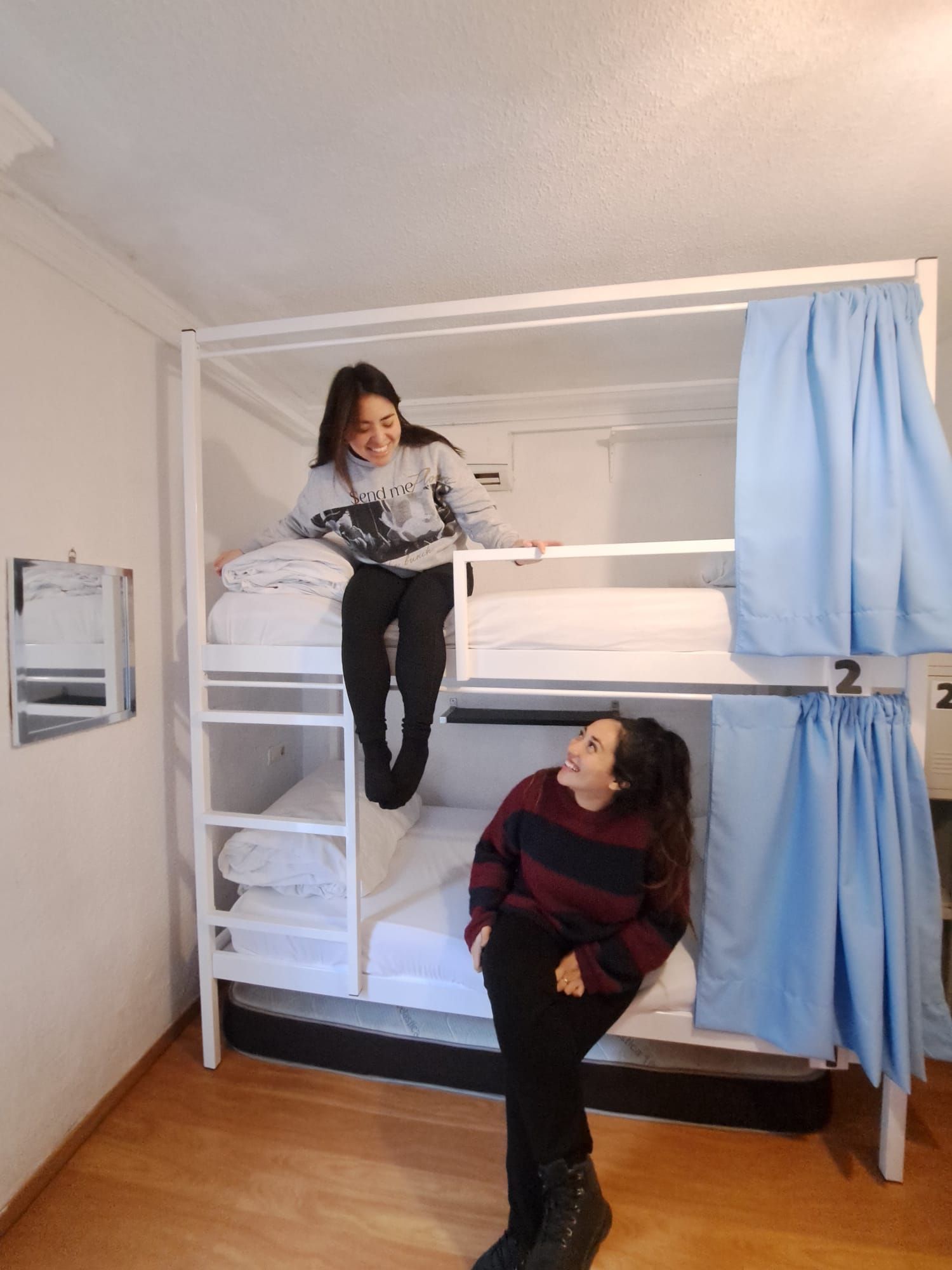 Habitación con literas, dos camas, un estante pequeño y una cortina.