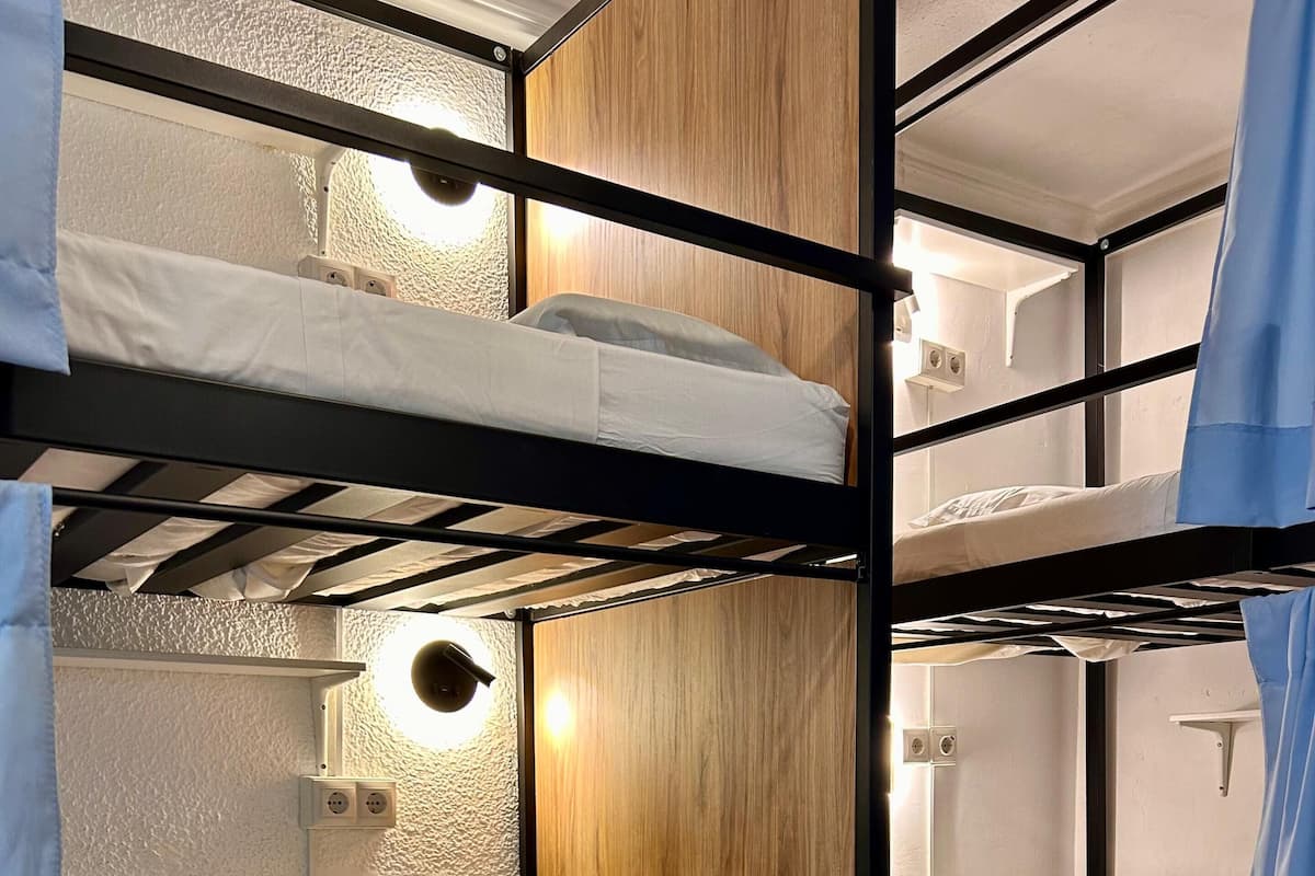 A bunk bed room with wooden paneling and a red rug. There are numbered storage compartments below the beds.