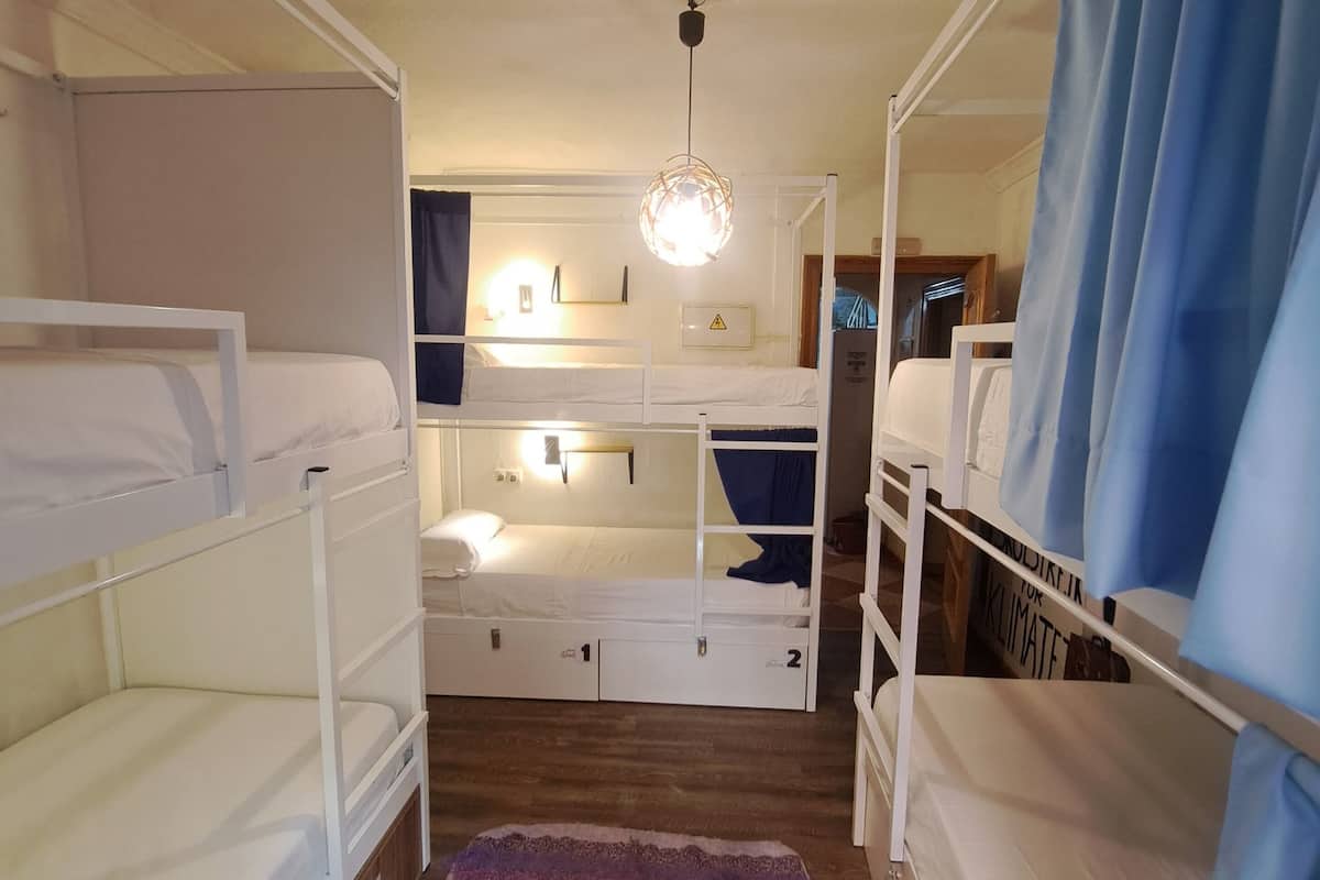 A bunk bed room with a wooden floor, a striped rug, and a ceiling light.