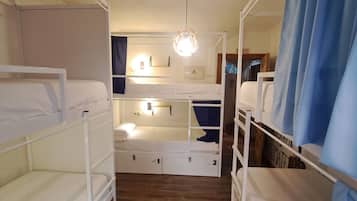 Quarto com beliche, piso de madeira, tapete listrado e luminária no teto.