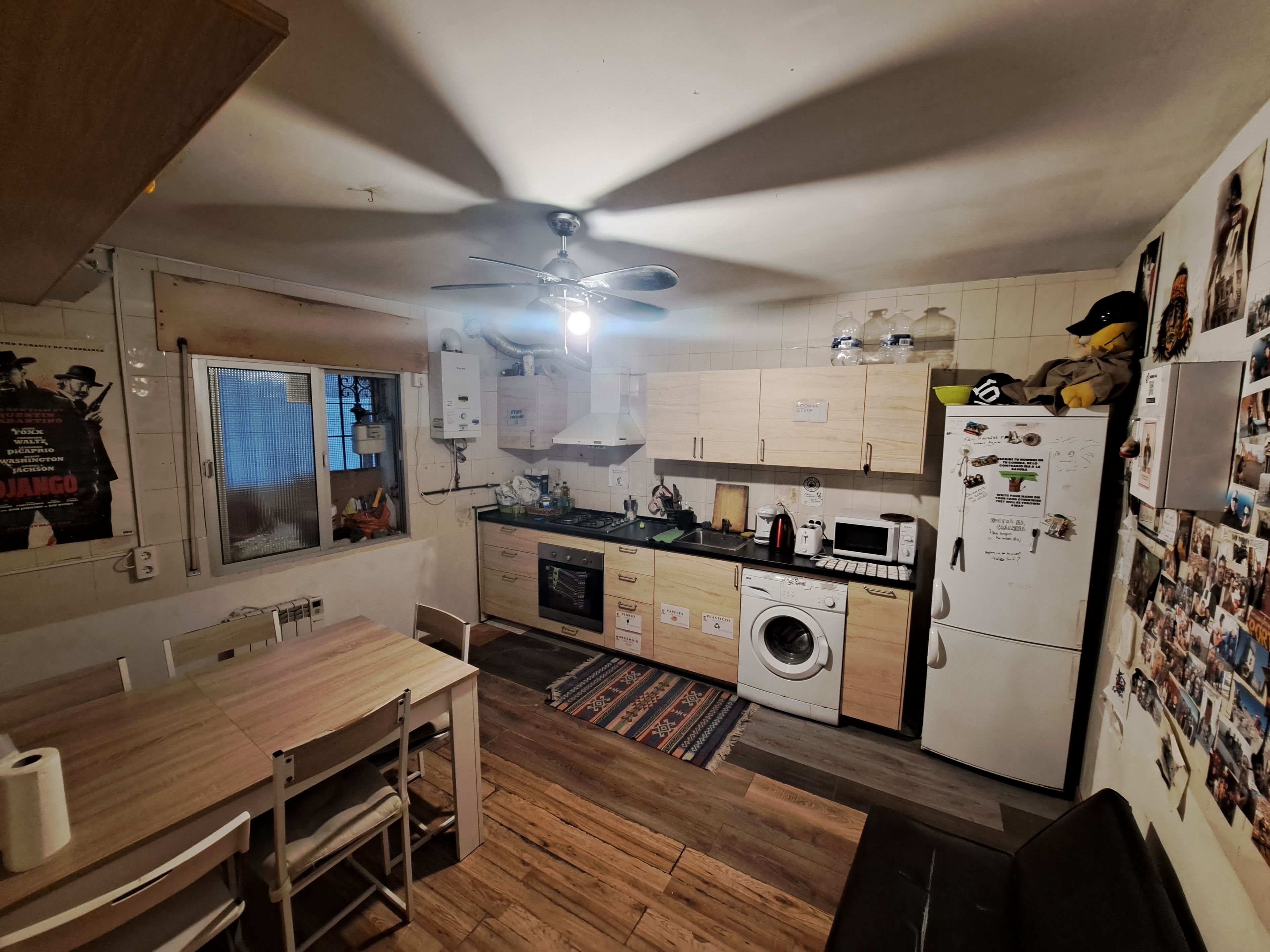 Una cocina compacta con armarios de madera, horno empotrado, microondas y lavadora.