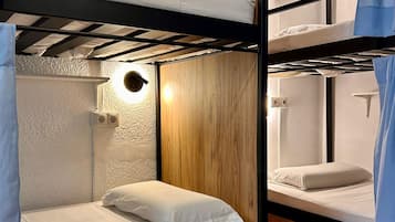 Quarto com beliches, painéis de madeira e tapete vermelho. Há compartimentos de armazenamento numerados abaixo das camas.