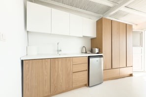 A modern kitchen with white cabinets, a stainless steel dishwasher, and a wooden cabinet.