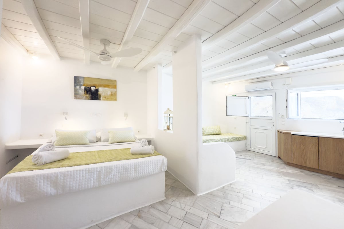 Habitació d'hotel moderna amb un llit, una zona de seients petita, una cuineta i un bany.