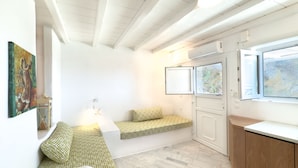 Une pièce avec une banquette intégrée, un lit, une fenêtre donnant sur un beau paysage et un tableau au mur.